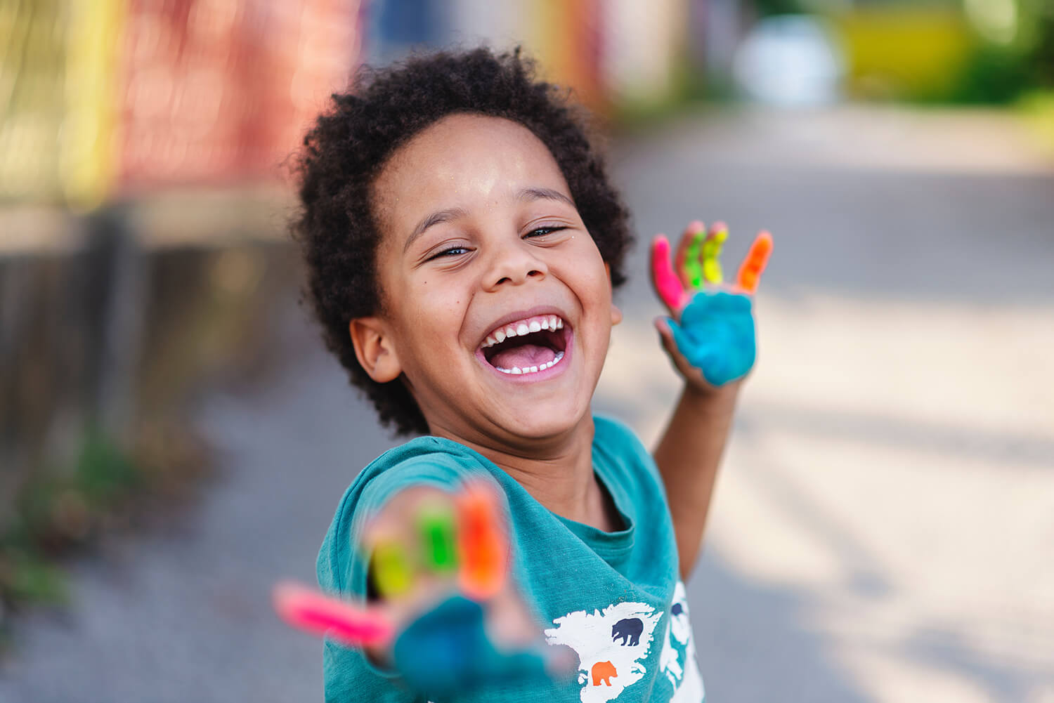 Smiling child with painted hands outdoors, representing joy and secure child arrangements in Cheshire.