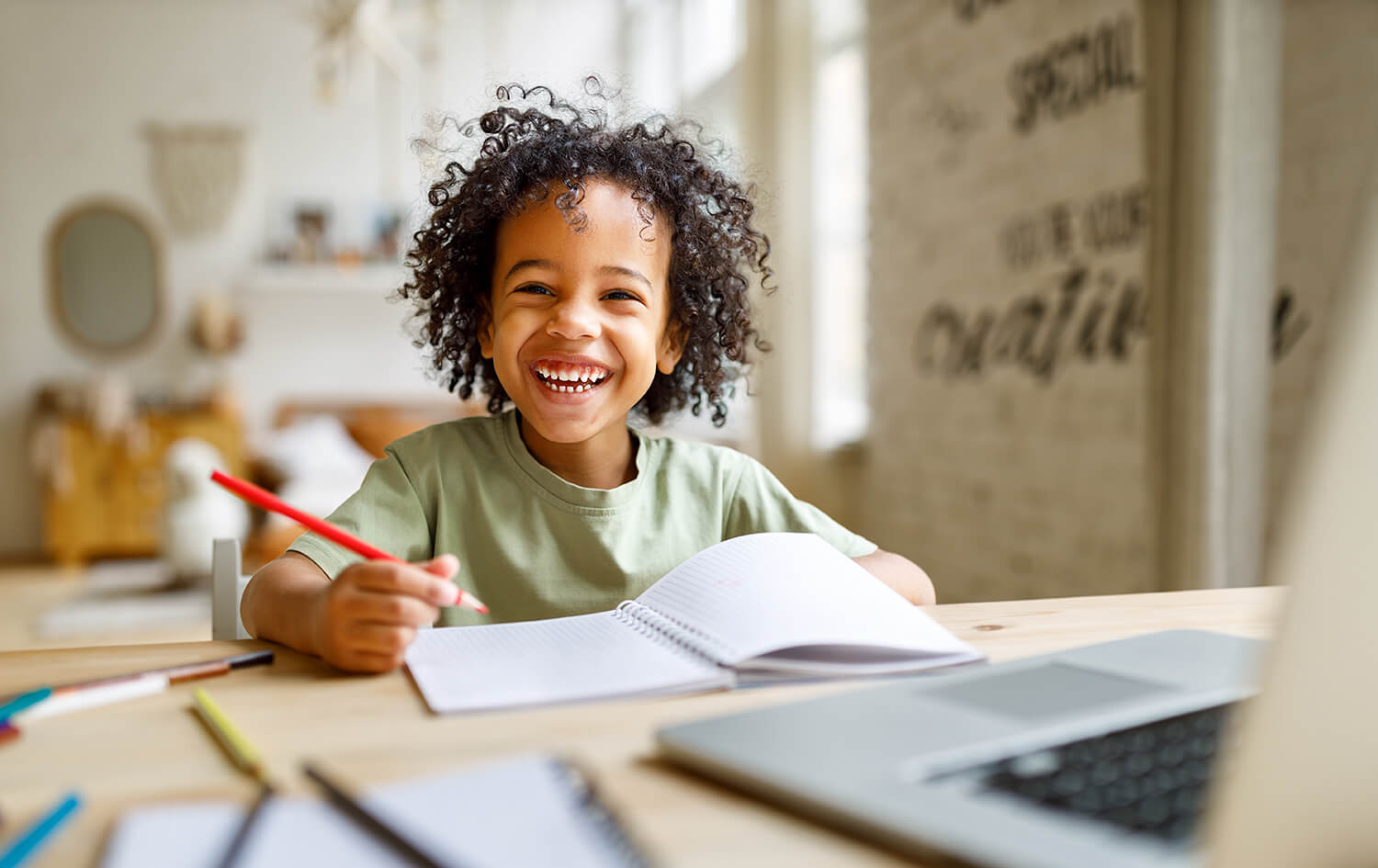 Smiling child writing in a notebook at home, symbolising stability in child arrangements in Cheadle Hulme.