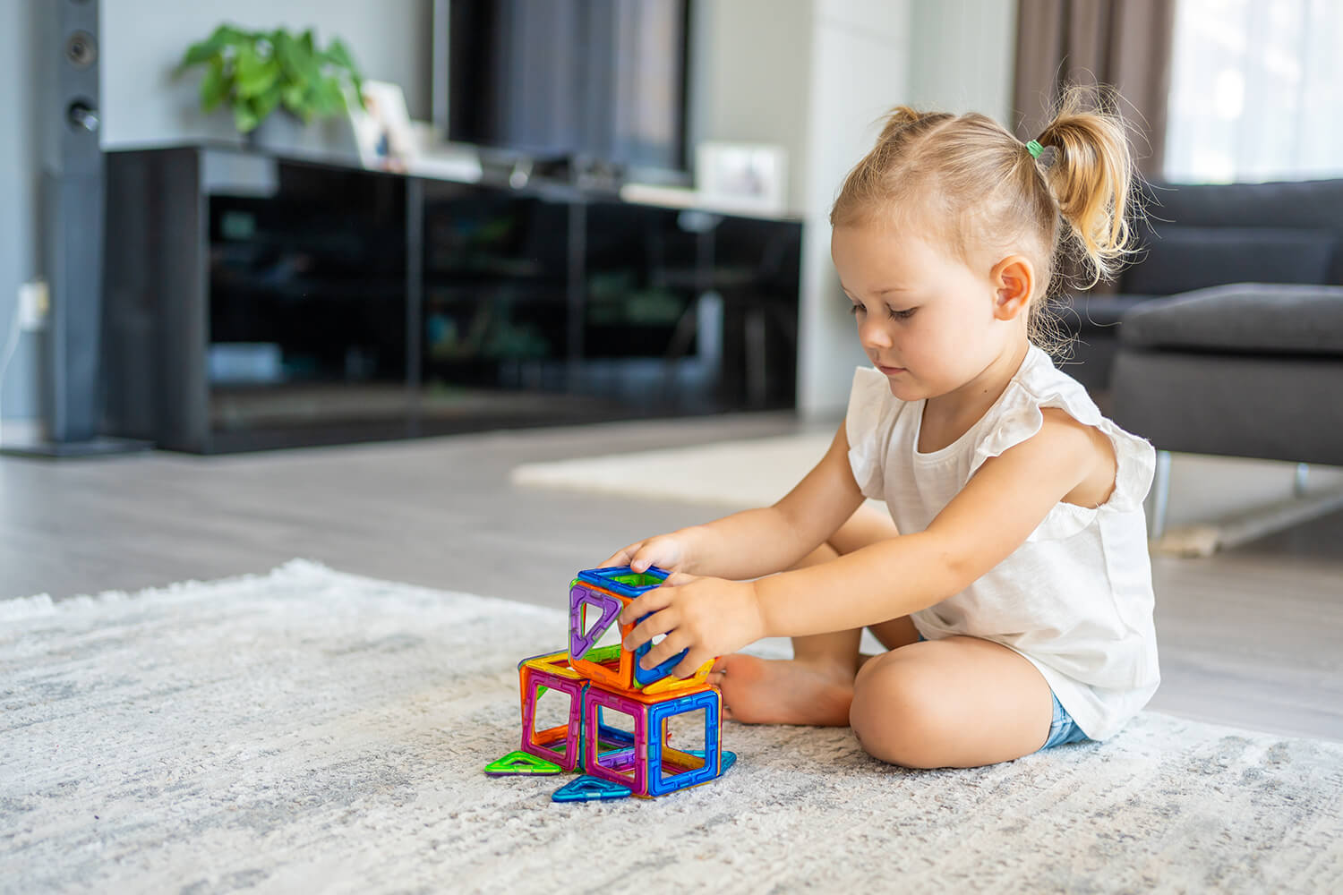 Young child playing with colourful building toys on the floor in a Nantwich family home.